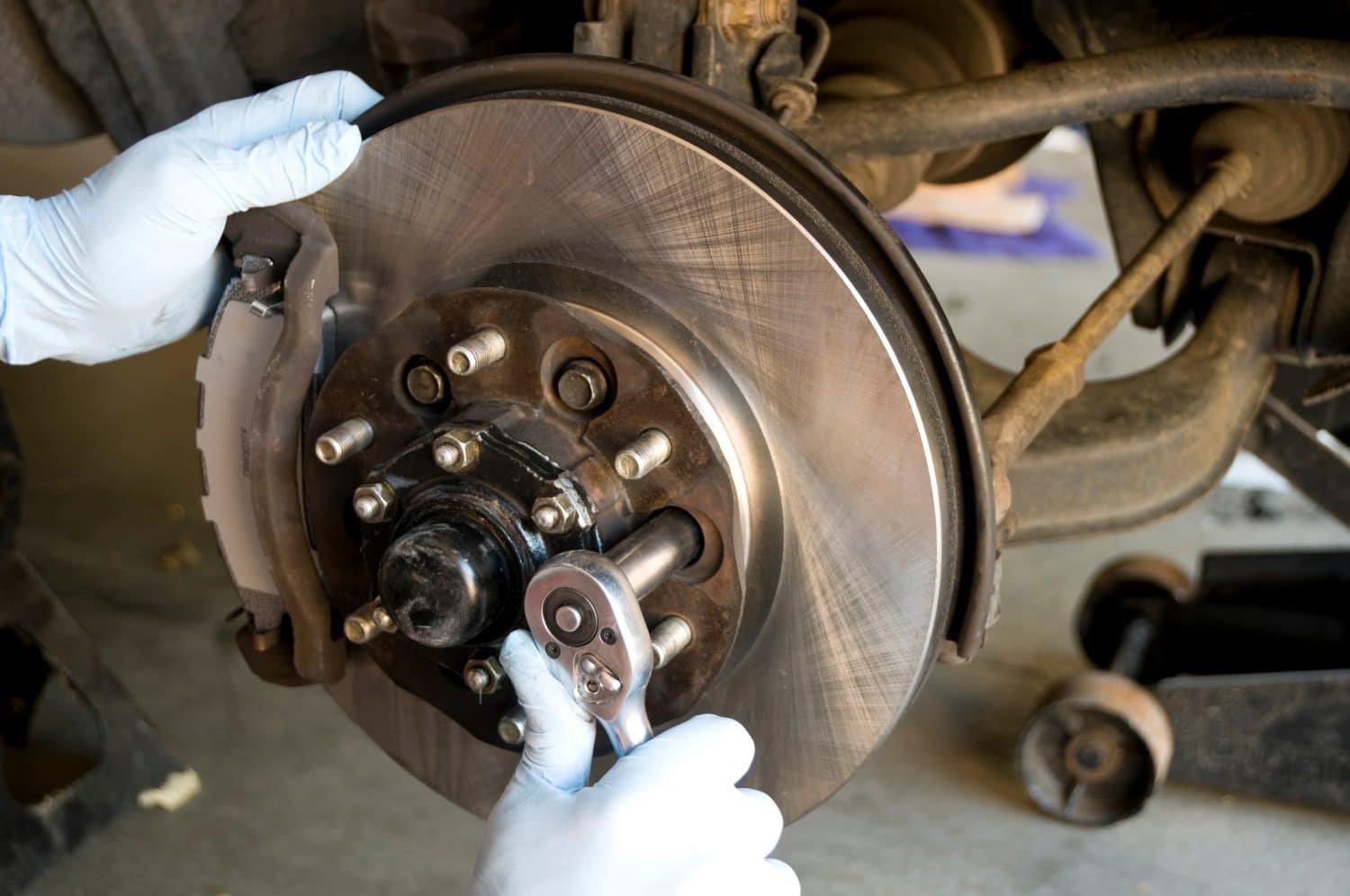 person in white gloves fixing brake rotors